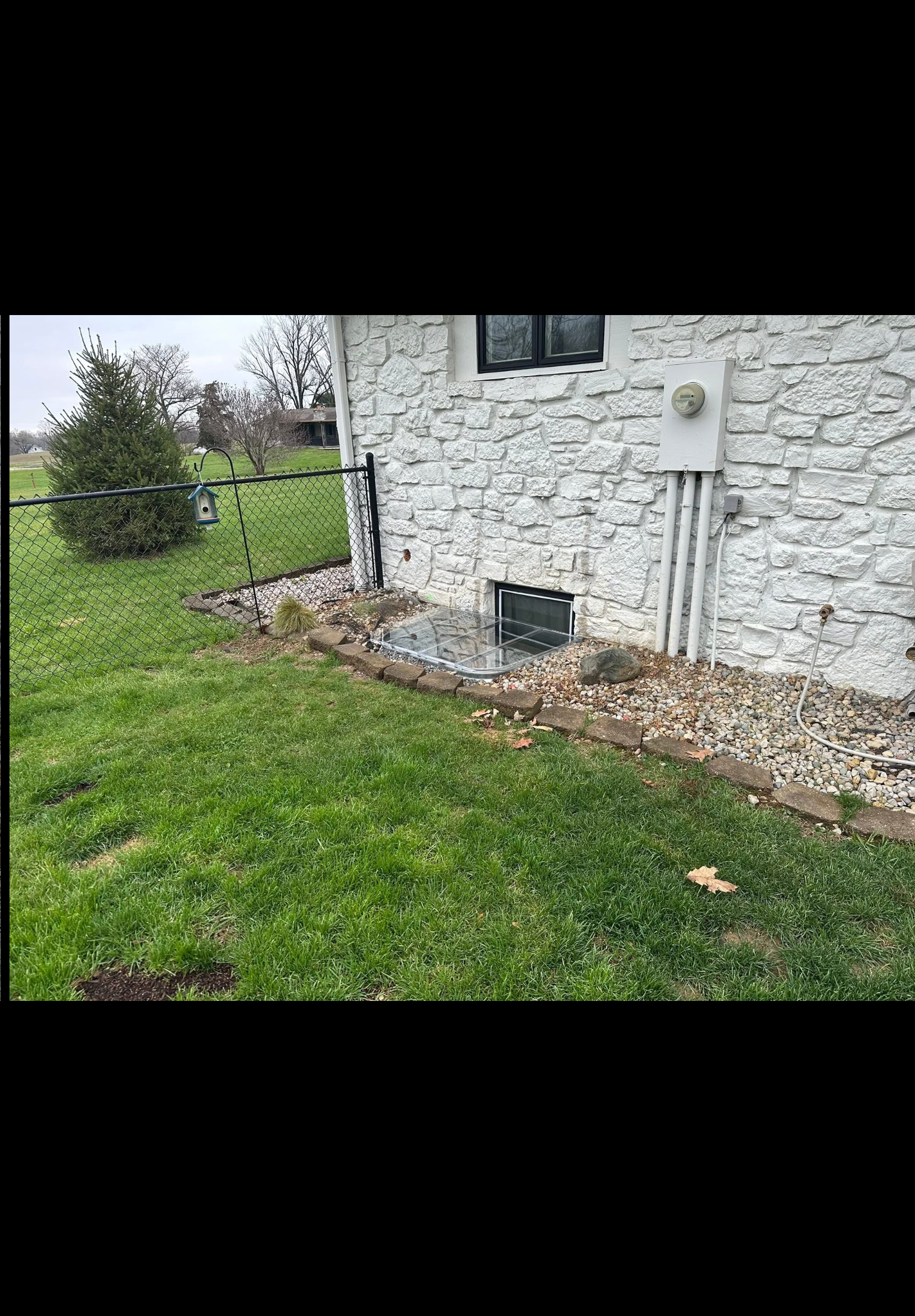 Completed window well installation with stone wall and gravel drainage